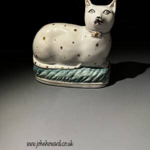 Staffordshire Pottery figure of a recumbent cat modelled on a turquoise base mid 19th century.